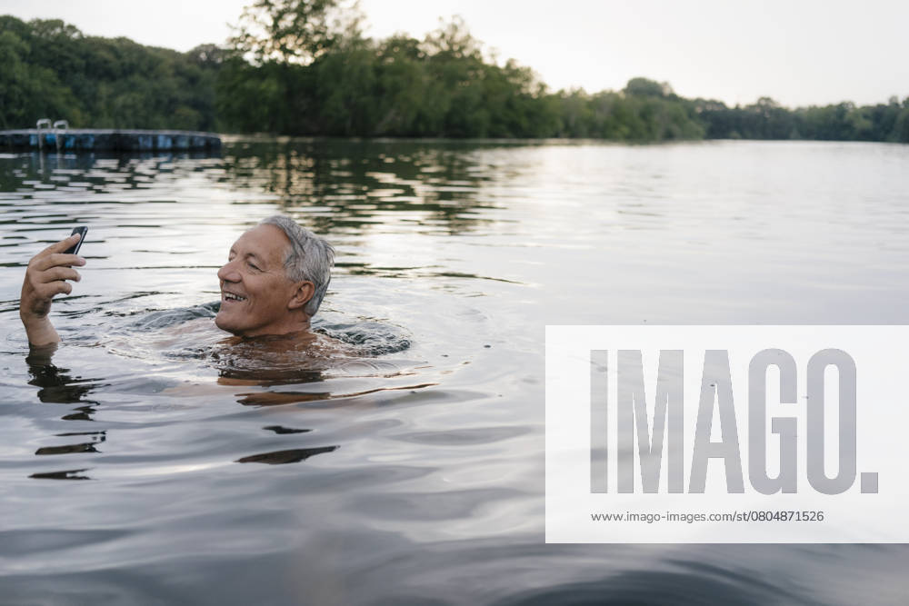 Senior man using cell phone in a lake model released, Symbolfoto, GUSF01807