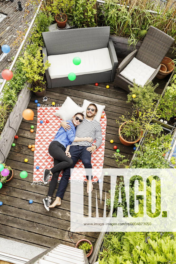 Young couple relaxing on their balcony, lying on blanket with arms around model released, Symbolfoto property released, PESF01172