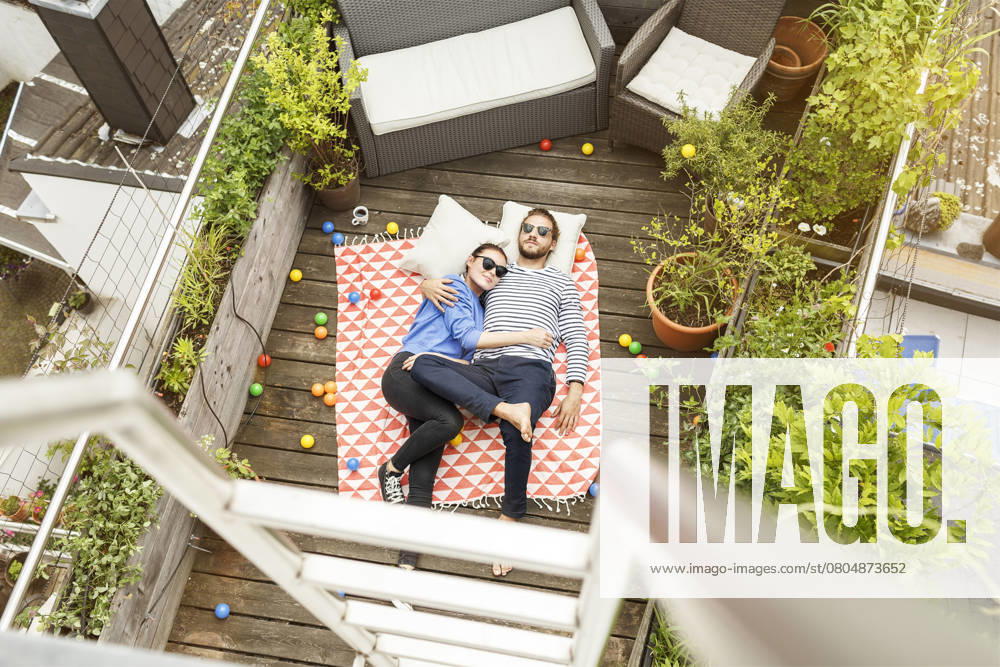 Young couple relaxing on their balcony, lying on blanket with arms around model released, Symbolfoto property released, PESF01173