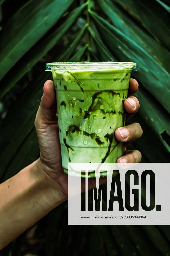 Iced Green matcha tea mixed with ice cube and milk in latte glass with green nature background , 51124234.jpg, hand, holding, latte, matcha, cup, iced, japanese, freshness, tea, cool, refreshing, healthy, asian, refreshment, green, table, beverage, summer, cold, tasty, cafe, nutrition, drink, cream, milk, natural, glass, smoothie, white, plant, leaf, nature, agriculture, isolated, environment, life, care, grow, gardening, concept, seedling, human, growing, ecology, leaves, garden, protection RECORD DATE NOT STATED