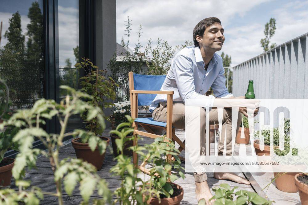Smiling man with bottle relaxing on balcony model released Symbolfoto property released JOSF01595