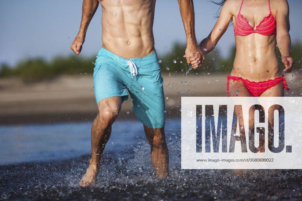 Couple holding hands splashing in water model released Symbolfoto VPIF00005