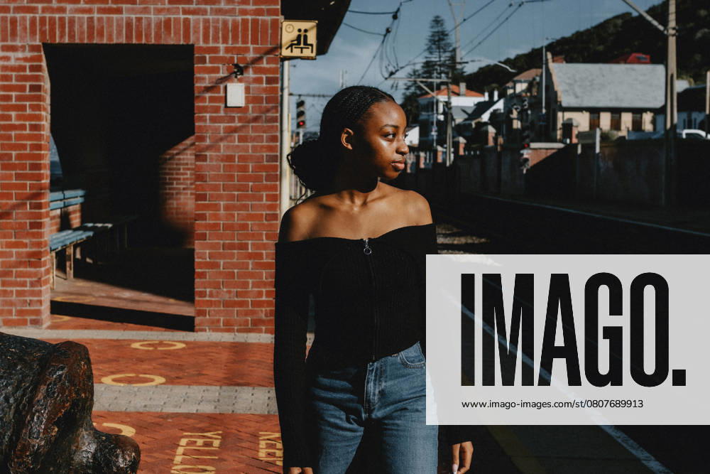 IMAGO Creative, Jahreszeit Sommer, Sommerferien Retro image of a young black female waiting for a train South Africa, Western Cape, Cape Town CR_YNJN250325-1691016-01 ,model released, Symbolfoto