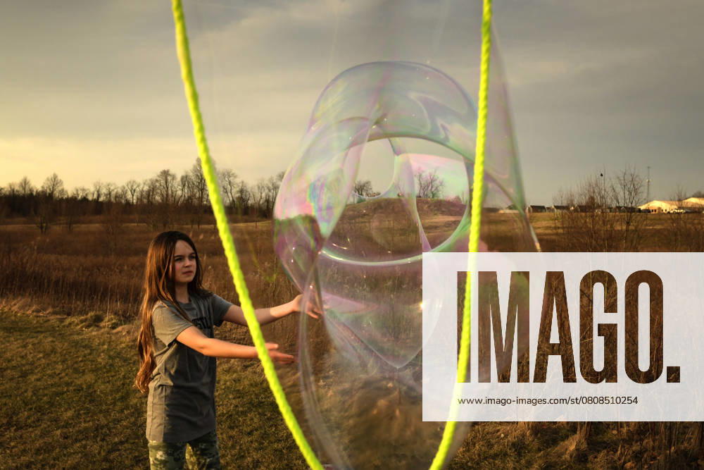 IMAGO Creative, Jahreszeit Sommer, Sommerferien Tween girl popping giant bubble in sunny field Wooster, Ohio, United States CR_JOKU250331B-1684840-01 ,model released, Symbolfoto