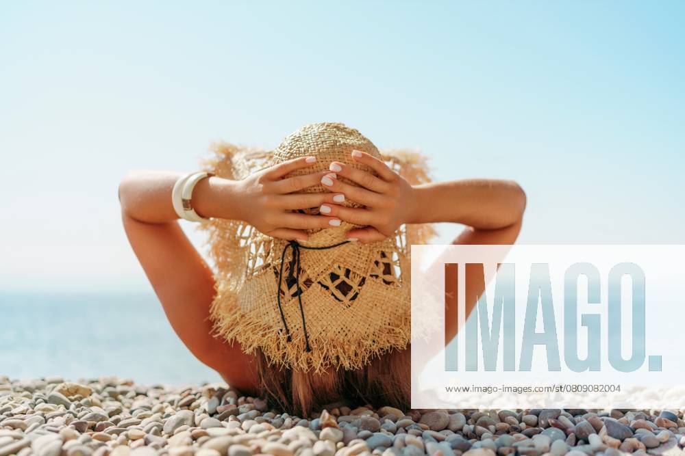 Beach Relaxation woman lies on a pebble beach, legs raised, and arms spread out. The concept of travel, vacation at sea., model released, , property released, , 57811536.jpg, beach, relaxation, sunshine, pebbles, water, clear skies, calmness, tranquility, nature, outdoors, serene, straw hat, shadows, highlights, relaxed, tranquil, waterside, sunlight, peaceful, mood, blue-green sea, individual, face down, legs raised, arms spread out. RECORD DATE NOT STATED