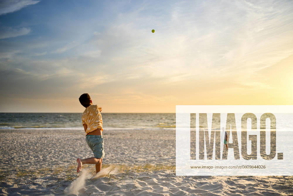 Boy throws ball to brother with beautiful sunset over the ocean Adelaide, South Australia, Australia CR_PAOL250404-1698017-01 ,model released, Symbolfoto