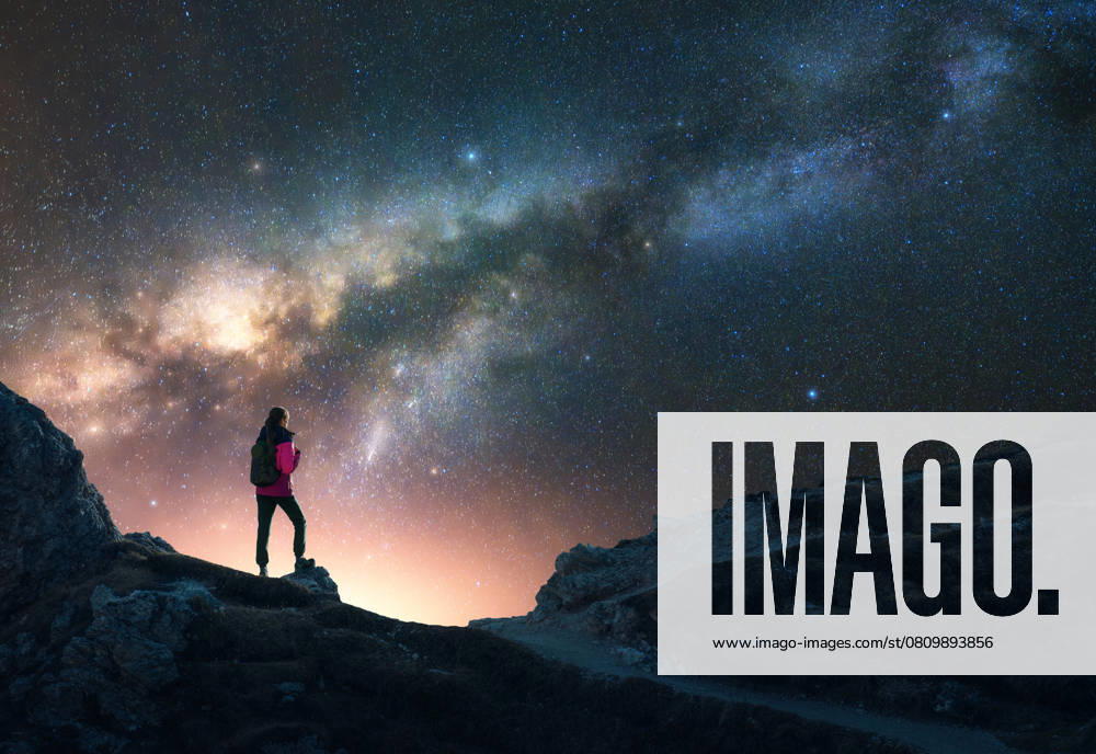 Glowing Milky Way and woman on mountain peak at starry night. Dolomites, Italy. Galaxy. Space landscape with silhouette of a girl, rocks, sky with bright stars. Milky Way and hiker. Nightscape Model Released DenisBilytskyi_ID27418_786784_013