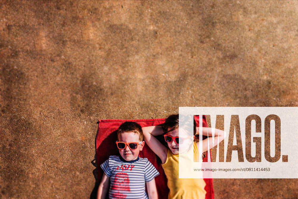 IMAGO Creative, Jahreszeit Sommer, Sommerferien Two kids laying on a towel in the sunshine with sunglasses Tulsa, Oklahoma, United States CR_KRRY250412-1661740-01 ,model released, Symbolfoto