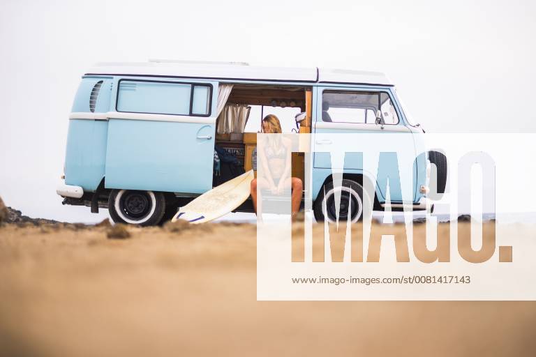 Young woman with surfboard sitting in van on the beach model released Symbolfoto SIPF01803