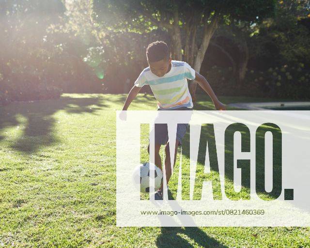 Boy dribbling black-and-white soccer ball across yard near pool under bright sunlight, lens flare Boy dribbling black-and-white soccer ball across yard near pool under bright sunlight, lens flare. Play, outdoor, vibrant, childhood, activity, relaxation, recreational, model released, , property released, , 12.05.2021, 5850575.jpg, soccer ball,dribbling,boy,outdoor,play,childhood,activity,relaxation,recreational,sunny,sunlight,lens flare,yard,grass,lawn,trees,shrubs,pool,african american,male,child,striped t-shirt,cargo shorts,sneakers,athletic,vibrant,green,foliage,summer,bright,sportive,movement,energy,healthy,youth,field,game,garden,natural,sunlit,casual,leisure,dynamic,active,happiness,single,grassland,sport,exercise