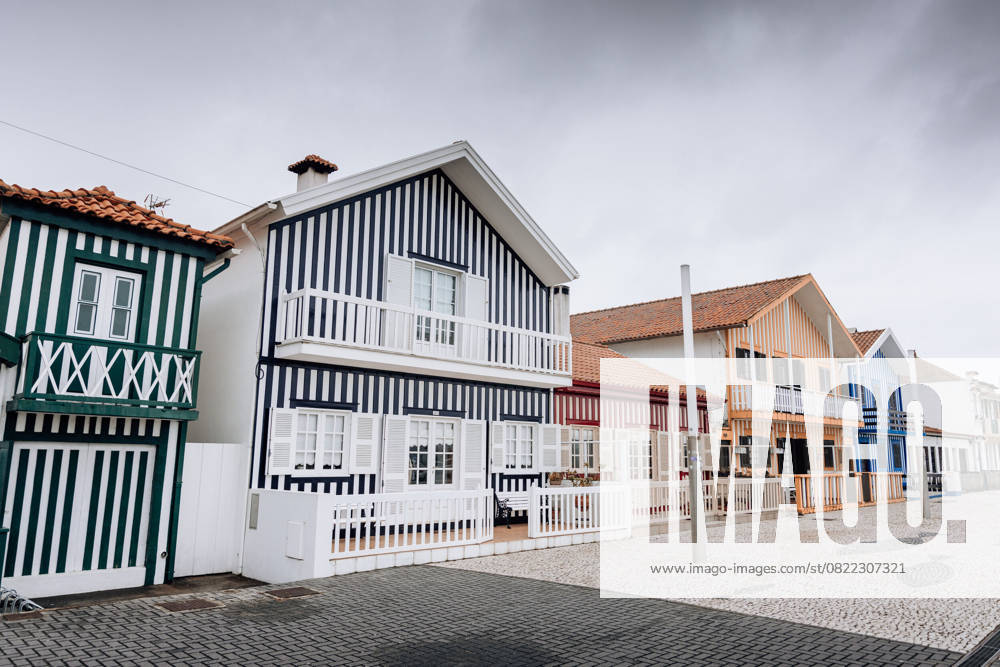 Colorful striped houses with balconies on a cobblestone street in Costa Nova do Prado, Portugal