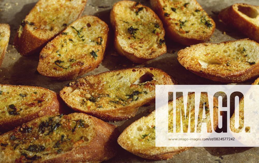Baguette Toasts, im Ofen gebacken, mit Knoblauchbutter und Kräutern, hausgemacht, auf einer Platte, Ansicht von oben Baguette toasts, baked in the oven, with garlic butter and herbs, homemade, on a platter, top view