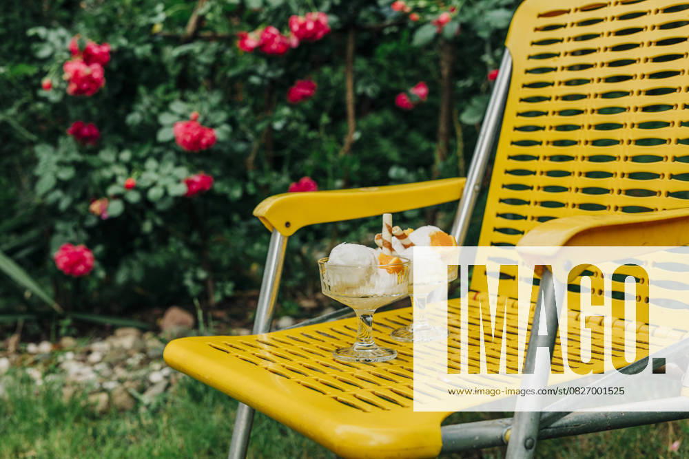 Ice cream on yellow armchair in summer garden setting outdoors, VSNF03579