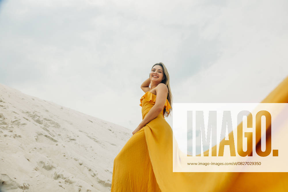 Creative Highlight Symbolbilder Woman in yellow dress walking on sandy beach dune outdoors smiling model released, Symbolfoto, VSNF03675
