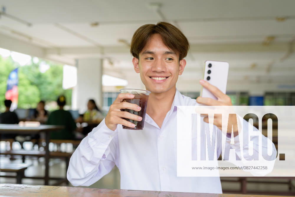 IMAGO Creative, Food, Trend, Iced Coffee Nicht-binärer Universitätsstudent, der auf dem College-Campus sitzt und telefoniert Nicht-binärer Universitätsstudent, der auf dem College-Campus sitzt und telefoniert (License=RF) ,model released, Symbolfoto
