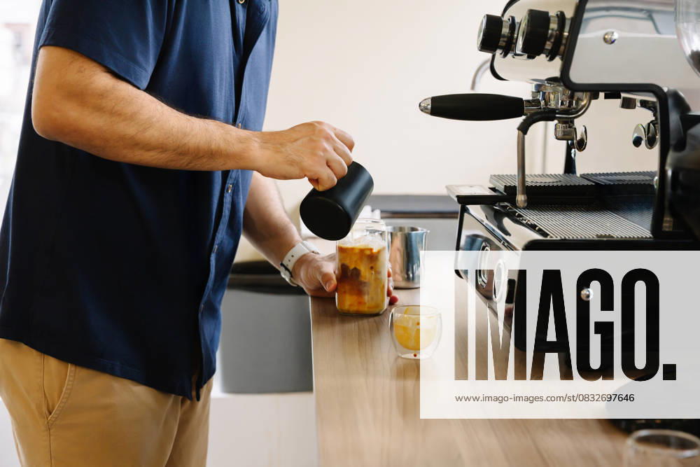 IMAGO Creative, Food, Trend, Iced Coffee PR_ID30758_11598_RandaStudio.jpg, MR_ID30758_22173_ClarenaSalamanca.jpg, MR_ID30758_22174_JorgeEnrriqueParrado.jpg, MR_ID30758_22175_LilianaAndreaLonga.jpg A man makes iced coffee in an office setting, using a modern coffee machine. This cozy setup inspires productivity and provides a refreshing break for coworkers and team members, Property released Model Released AngelaRober_ID30758_1041693_002