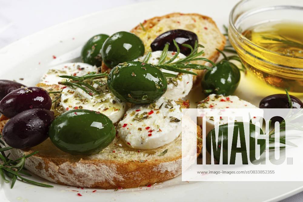 Ein Teller mit einem Snack, Ciabatta Brot mit Käse und Oliven, Olivenöl, Gewürzen und Kräutern, Blick von oben, keine Menschen A plate with a snack, ciabatta bread with cheese and olives, olive oil, spices and herbs, top view, no people