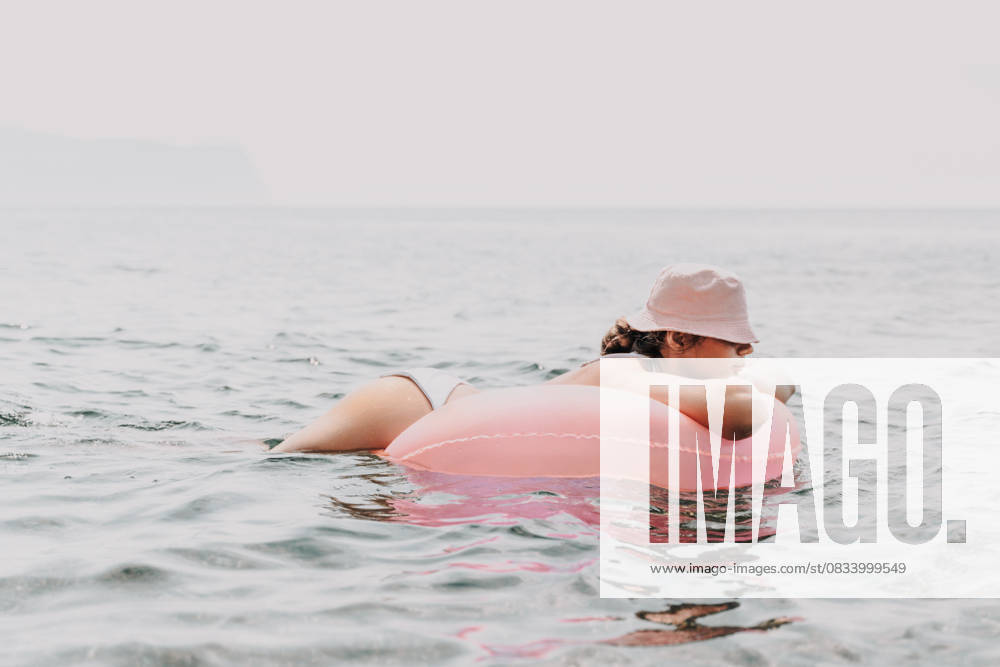 A woman is laying on a pink inflatable raft in the ocean. The scene is peaceful and relaxing, with the woman enjoying the water and the sun. A woman is laying on a pink inflatable raft in the ocean. The scene is peaceful and relaxing, with the woman enjoying the water and the sun, model released, , 96714612.jpg RECORD DATE NOT STATED