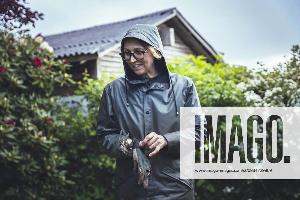IMAGO Creative, Jahreszeit Sommer, Regen, Sommerregen Woman With Gardening Gloves Surrounded By Lush Nature Haarby, Denmark CR_EMWIXA250917-1832601-01 ,model released, Symbolfoto