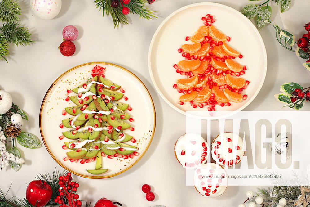 Weihnachts- und Neujahrsgerichte. Essbare Weihnachtsbäume aus Mandarinen, Kiwi und Granatapfel für eine festliche Tafel, eine Idee für die Dekoration von Lebensmitteln und die Dekoration von Silvestergerichten für Kinder Weihnachts- und Neujahrsgerichte. Essbare Weihnachtsbäume aus Mandarinen, Kiwi und Granatapfel für eine festliche Tafel, eine Idee für die Dekoration von Lebensmitteln und die Dekoration von Silvestergerichten für Kinder (License=RF)