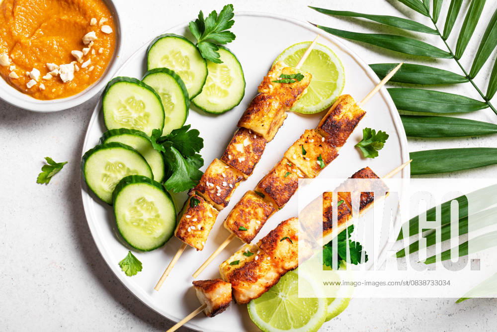 Gegrillte Tofu-Satay-Spieße und scharfe Erdnuss-Sauce Grilled tofu satay skewers and peanut spicy sauce on white plate close up.. Asian vegan vegetarian lunch, thai style food. (License=RF)