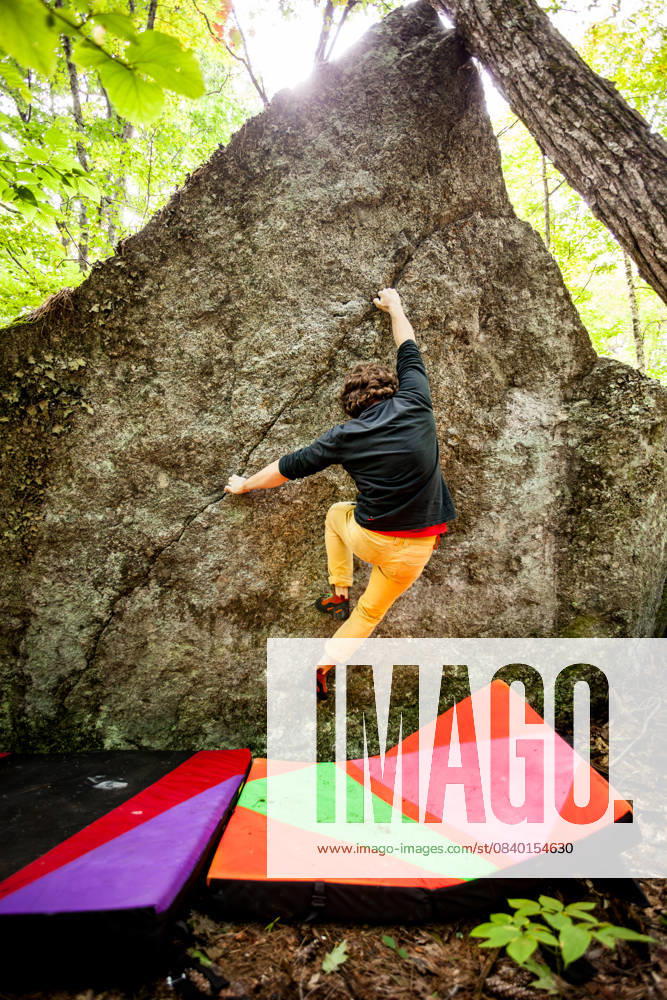 A rock climber climbs the face of a boulder with crash pads below United States, New Hampshire, Keene CR_VAWG251110-1874753-01 ,model released, Symbolfoto