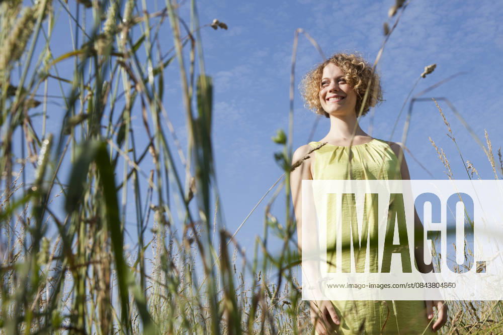 Smiling person in summer dress standing in tall grass outdoors in Munich model released, Symbolfoto, LDF000853