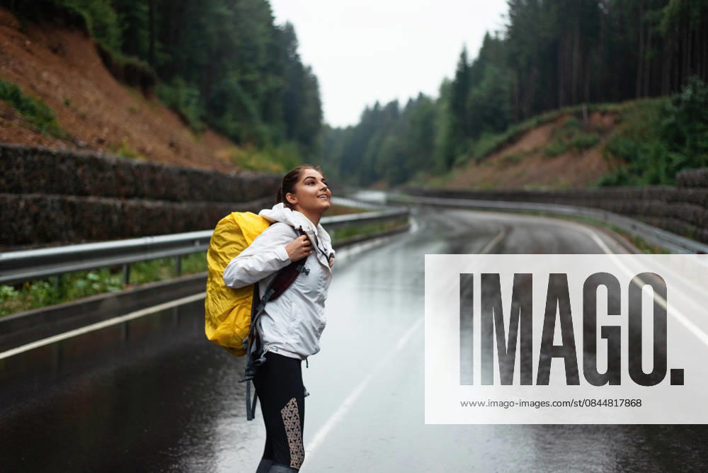 IMAGO Creative, Jahreszeit Sommer, Regen, Sommerregen Girl with a yellow backpack stands on a wet road looking up at the sky Bukovel, Ivano-Frankivsk Oblast, Ukraine CR_JUCE260104-1929688-01 ,model released, Symbolfoto
