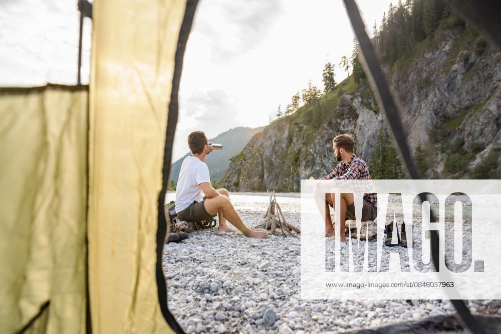 Brothers relaxing by riverside campfire during summer hiking adventure model released, Symbolfoto, DIGF26327