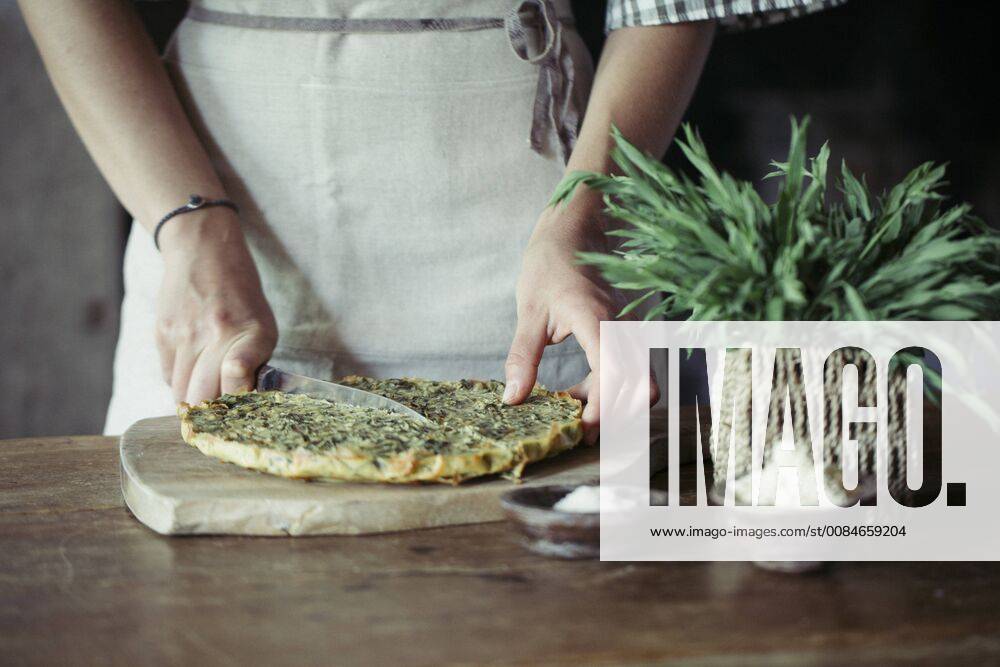 Young woman slicing homemade chickpea and herb cake model released Symbolfoto ALBF00424