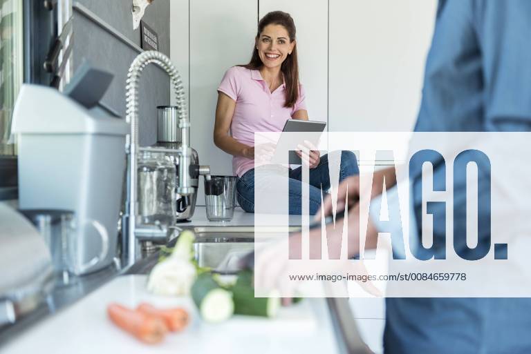 Happy couple in kitchen at home cooking and using a tablet model released Symbolfoto property released DIGF04442