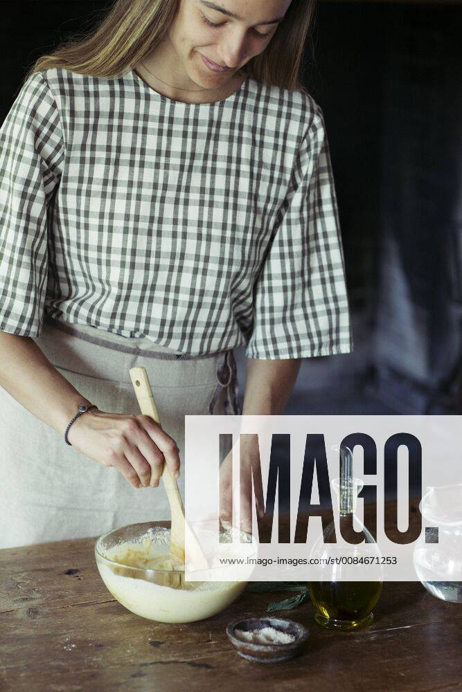 Young woman in kitchen preparing dough for fresh chickpea cake model released Symbolfoto ALBF00448