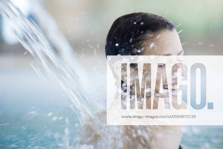 Woman relaxing under fountain in pool