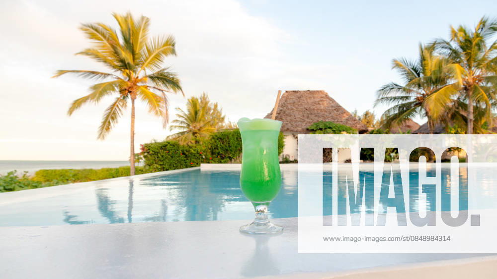 Honeymoon paradise at a Zanzibar resort pool A refreshing green cocktail by the pool at a luxurious Zanzibar resort. The serene background includes palm trees and a thatched villa, reflecting paradise. Model Released SilviaRedondo_ID33141_1127805_024