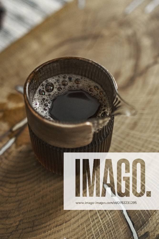 IMAGO Creative, Food, Trend, Iced Coffee Eine schicke Kaffeetasse auf einem rustikalen Holztisch, die das reichhaltige Gebräu und die einladende Textur des Getränks zur Geltung bringt A chic coffee mug on a rustic wooden table that showcases the drink s rich brew and inviting texture