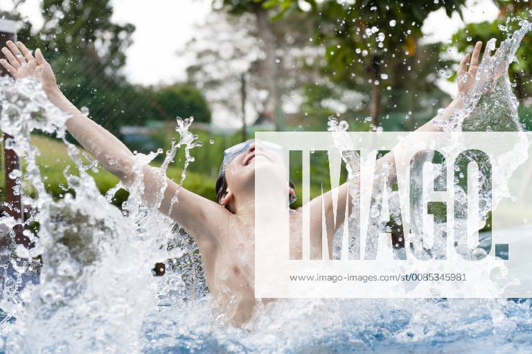 IMAGO Creative, Jahreszeit Sommer, Sommerferien Boy splashing in swimming pool