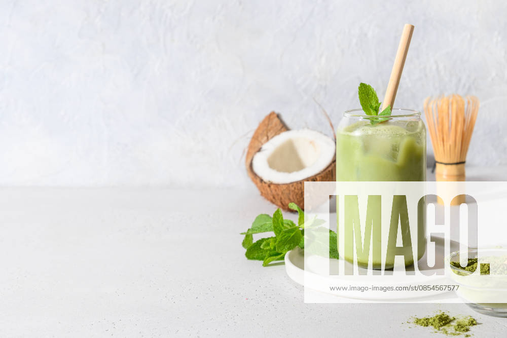 Eis-Latte mit grünem Matcha-Tee und Kokosmilch, garniert mit Minze, auf weißem Hintergrund. Iced latte green matcha tea with coconut water garnish mint on white background. Copy space. (License=RF)
