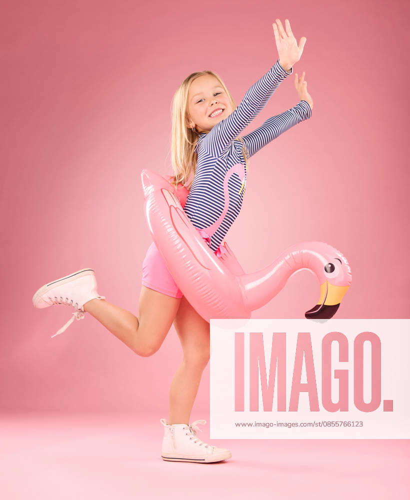 Playing, excited and portrait of girl and pool float for swimming, sea and summer. Youth, funny and inflatable with child and flamingo ring for relax, cute or beach holiday on pink background studio. (License=RF) ,model released, Symbolfoto