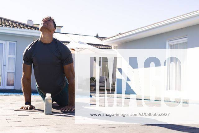 Man stretching back on paved poolside patio in dark sports shirt and shorts near water bottle, model released, property released, 27.03.2025 06:00:00, 11794033