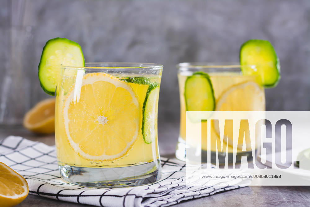 Erfrischende Limonade mit Zitrone, Gurke und Eis in Gläsern auf dem Tisch Refreshing lemonade with lemon, cucumber and ice in glasses on the table (License=RF)