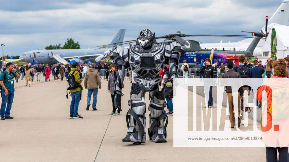 Trade visitor day at ILA Berlin 2026, Berlin, 12 06 2026 A person in an oversized robot costume with Bundeswehr emblem walks across the ILA exhibition grounds Military aircraft and a Bundeswehr helicopter as well as numerous visitors are visible in the background Schöneberg Berlin ExpoCenter Airport Brandenburg Germany 20260612-1V9A1881-M4000