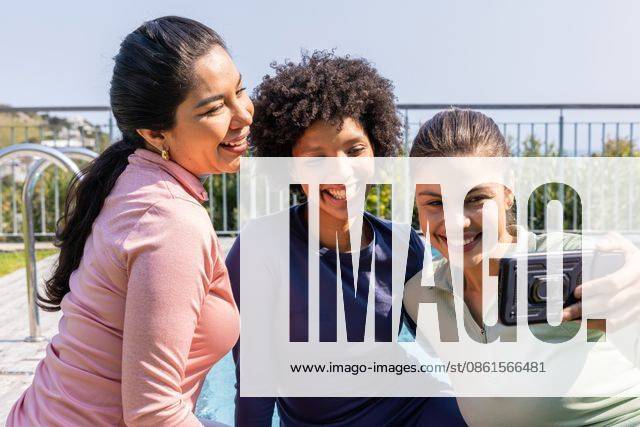 Diverse female friends posing for selfie poolside in long-sleeve athletic tops holding smartphone, model released, property released, 26.08.2025 06:00:00, 7967313