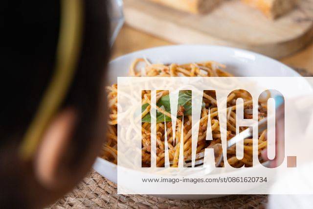 Child holding fork with turquoise nails, twirling spaghetti with basil in white bowl at table, model released, property released, 03.07.2025 06:00:00, 6981104