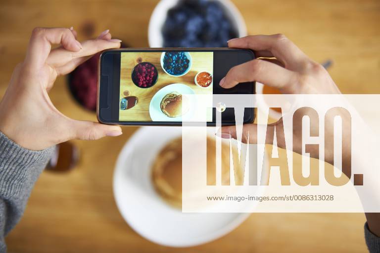 Young woman taking pictures of breakfast pancakes with berries and fresh fruit model released Symbolfoto property released ABIF00927