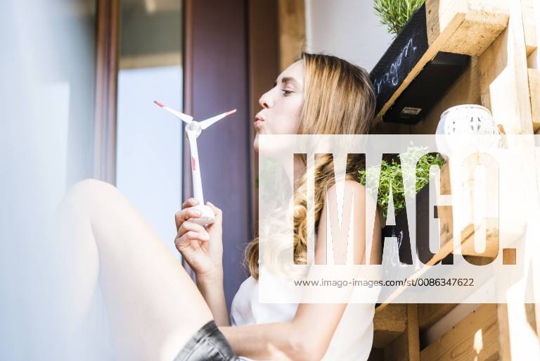 Woman at herb garden on balcony blowing model wind turbine model released Symbolfoto property released JOSF02595