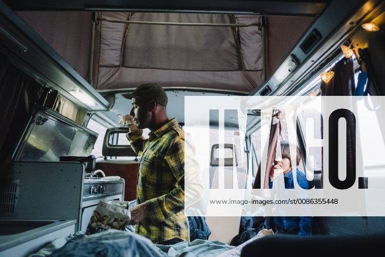 IMAGO Creative: Klimawandel - Nachhaltiges Reisen Man cooks in camper van as his son looks from the door, Tenerife, Canary Islands, Spain, Tenerife Canary Islands Spain VISE003976 model released Symbolfoto
