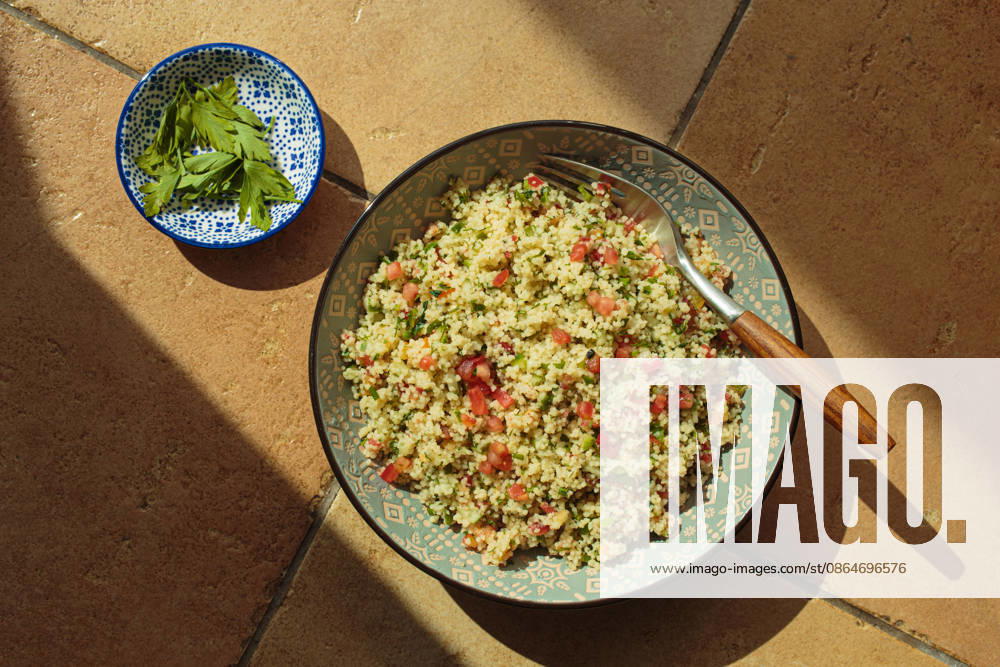 Tabbouleh-Salat, Couscous, Gemüse, Draufsicht, natürliches Sonnenlicht, Terrakotta Middle Eastern tabbouleh salad, a healthy vegan mediterranean dish, top view sun light hard shadows terracotta (License=RF)