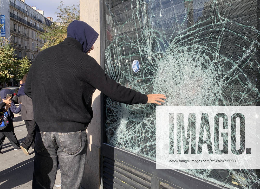 A man feels a shattered shop window near Republique Square in Paris, on Sunday, October 18, 2026. Residents awoke to scenes of widespread damage with shopfronts shattered, burnt out cars, charred bikes, and piles of glass and debris on the pavements of the French capital a day after riots erupted during protests against rising fuel prices, the cost of living and deteriorating public services, including schools. PAR20261018115 MAYAxVIDON-WHITE