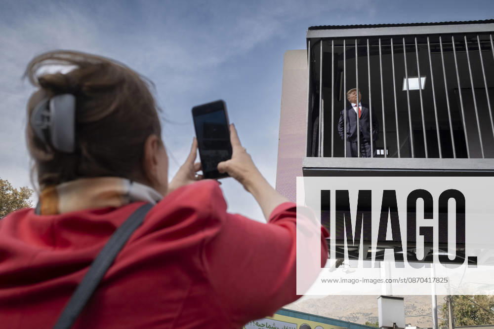 Anti-U.S. President Trump Performance On Billboard Reactions An Iranian woman films a masked man (not pictured) performing as U.S. President Donald Trump inside a symbolic cell mounted on a billboard in northern Tehran, Iran, on October 22, 2026, amid escalating tensions between Iran and the United States. Tehran Tehran Iran