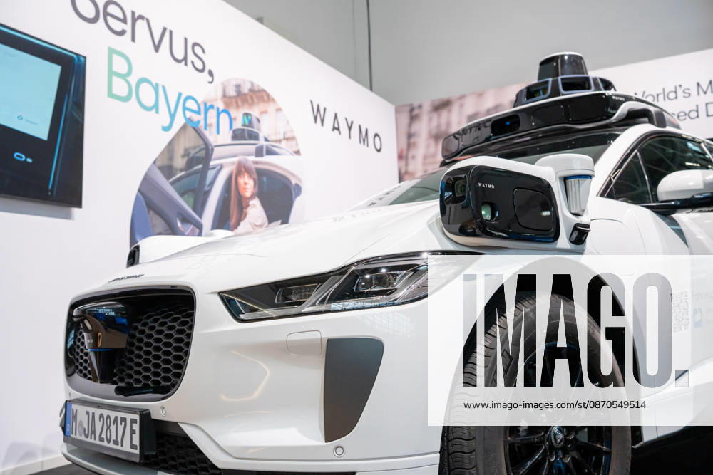Munich, Bavaria, Germany October 23, 2026: The 2026 convention of the CSU (Christian Social Union) party at the Munich Trade Fair Center. Background image: a close-up of a white Jaguar I-PACE equipped with autonomous driving technology from the U.S. company Waymo. The electric vehicle is equipped with cameras, LiDAR, and radar sensors for AI-assisted detection of its surroundings and is designed for use as a self-driving robotaxi